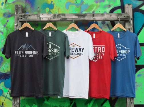 Sample design mockup: five tees on a rack with fictional business logos printed on grey, green, white, red, and blue shirts